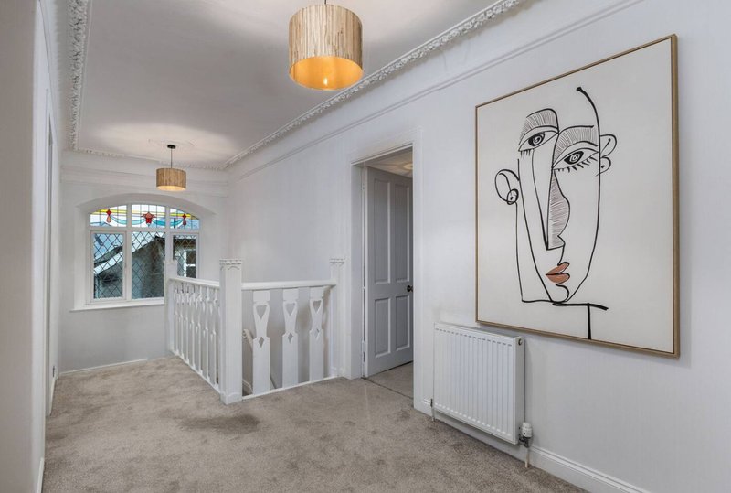 Bright hallway with staircase, pendant lighting, abstract line art on wall