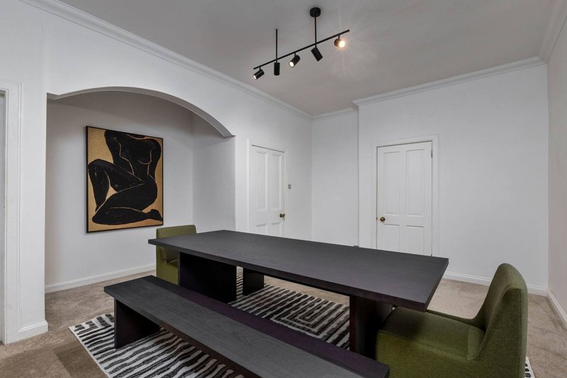Modern dining room with black table, bench seating, green armchair and abstract wall art