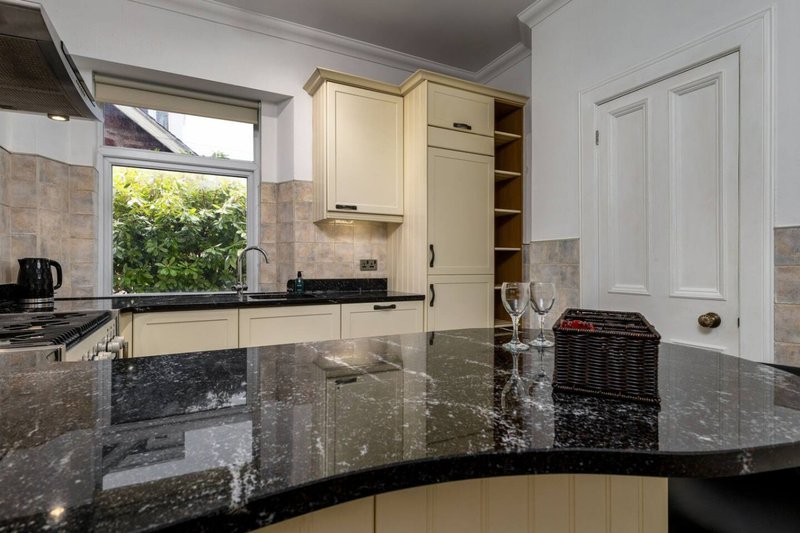 Modern kitchen with cream cabinets, black granite countertop, and window overlooking garden
