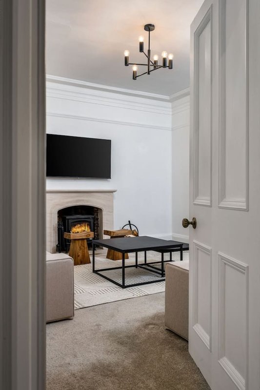 Modern living room with fireplace, wall-mounted TV, black coffee table and pendant lighting