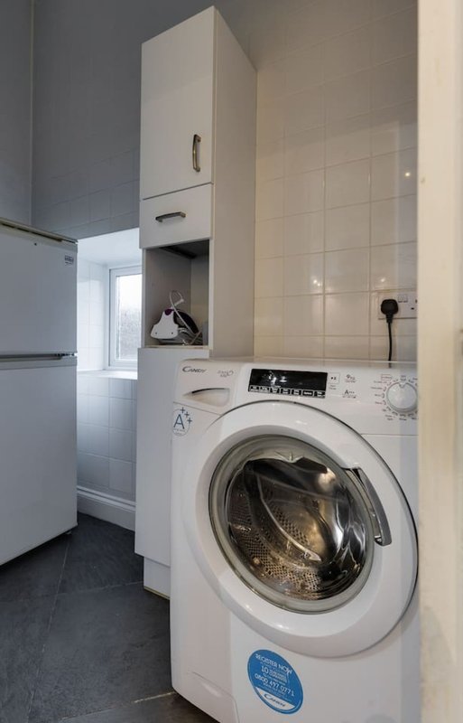 Utility room with white washing machine, wall-mounted storage cabinet, and refrigerator