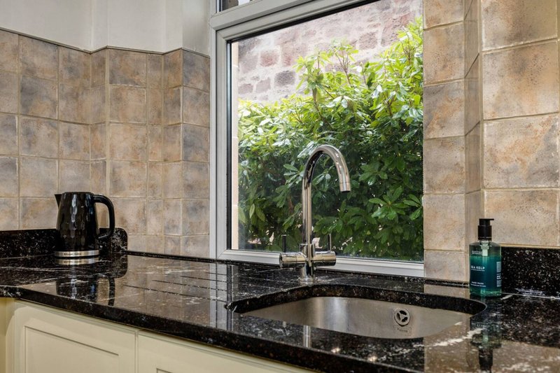 Kitchen with black granite countertop, chrome faucet, and window overlooking garden