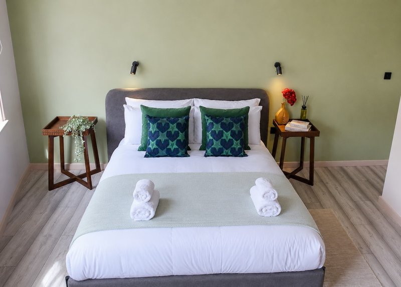 Bedroom with gray upholstered bed, white bedding, decorative pillows, and rolled towels