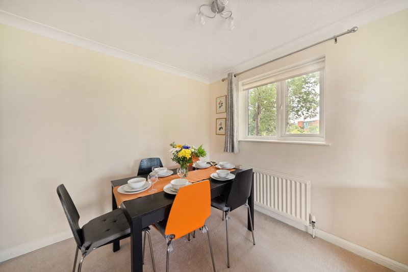 Dining room with black table, orange and black chairs, place settings, and window with garden view