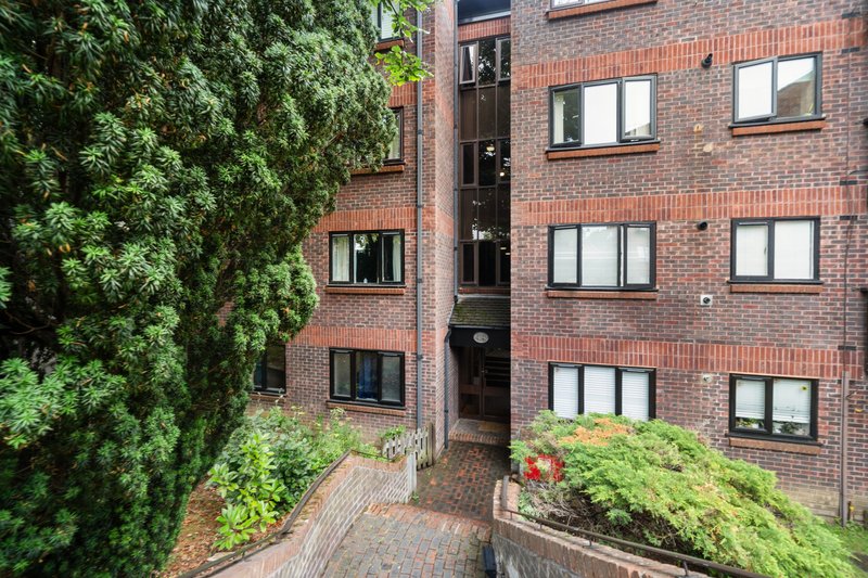 Brick apartment building exterior with ivy-covered walls, central entrance and planters