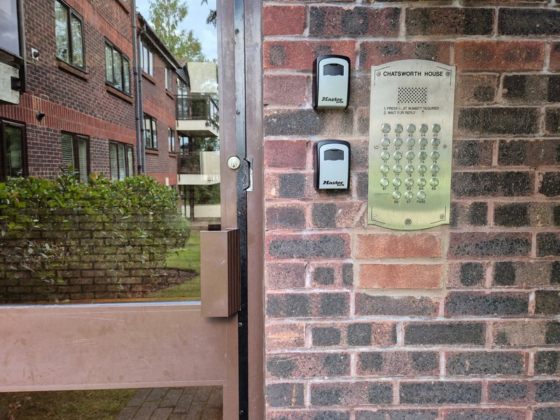 Brick building exterior with entrance gate, intercom system and keypad mounted on wall