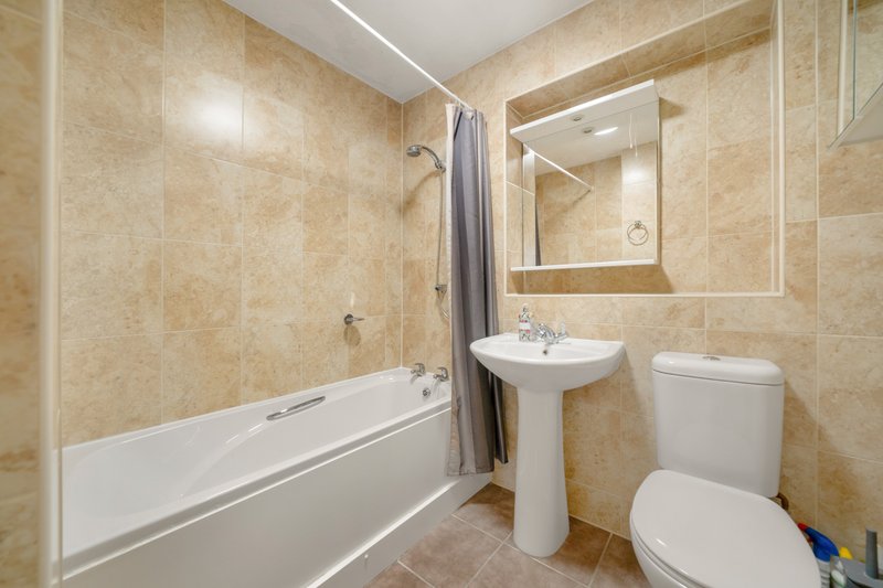 Family Bathroom with bathtub and shower, pedestal sink, toilet, mirror and beige tile walls