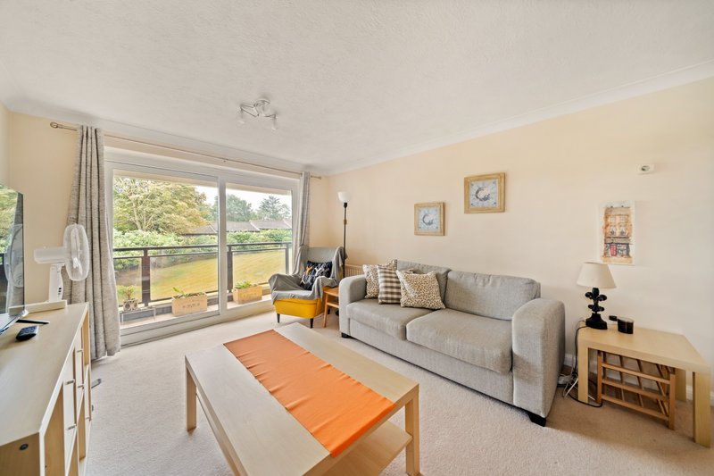 Bright living room with grey sofa, orange coffee table, large windows and garden view