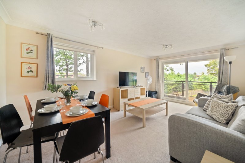 Open-plan living area with dining table, sofa, TV, and garden views through large windows