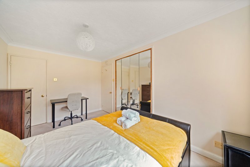 Bright bedroom with double bed, yellow bedding, desk, wardrobe and mirrored doors
