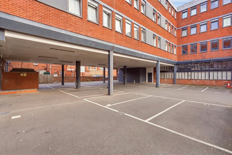 Brick building exterior with covered parking area and courtyard, daytime