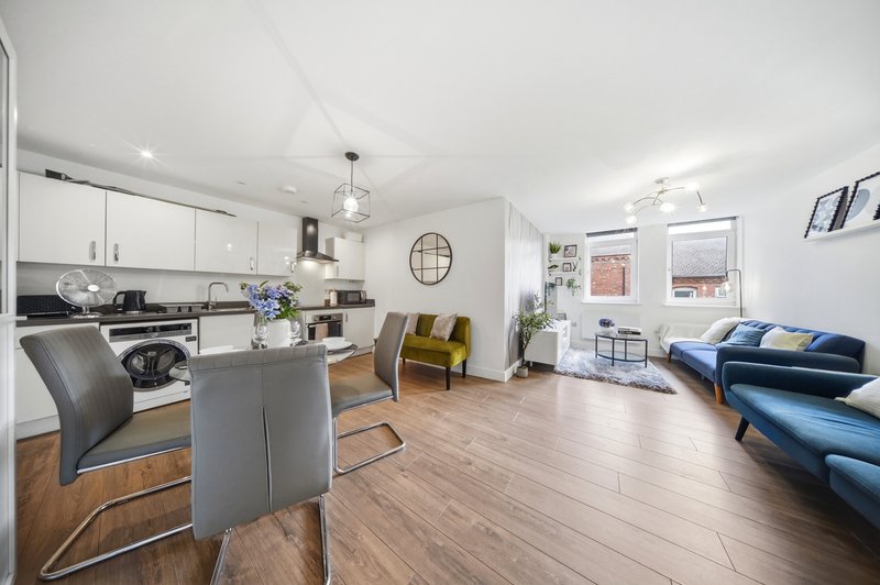 Open-plan kitchen and living area with white cabinetry, dining table, and blue sofa