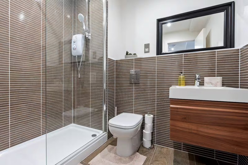 Modern bathroom with tiled shower enclosure, toilet, wooden vanity and mirror