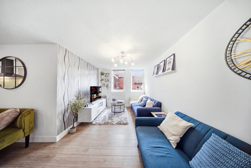 Bright living room with blue sofa, wooden flooring, wall art, and modern furnishings
