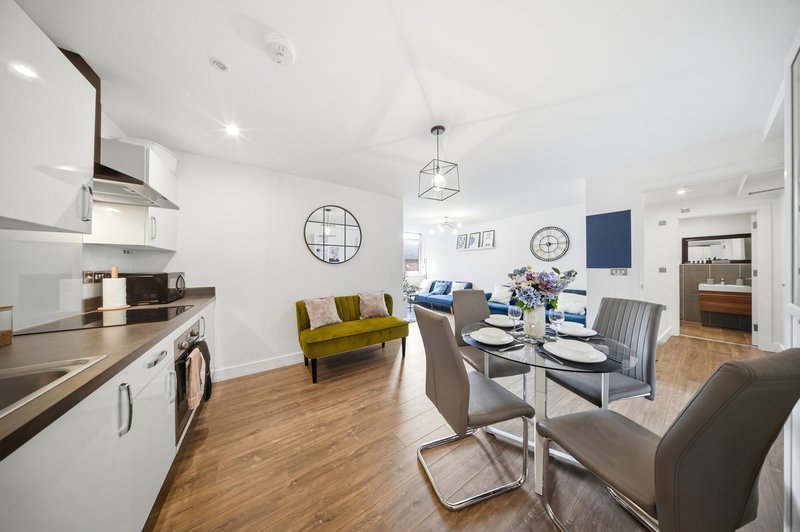 Open-plan kitchen and living area with dining table, sofa, and modern appliances