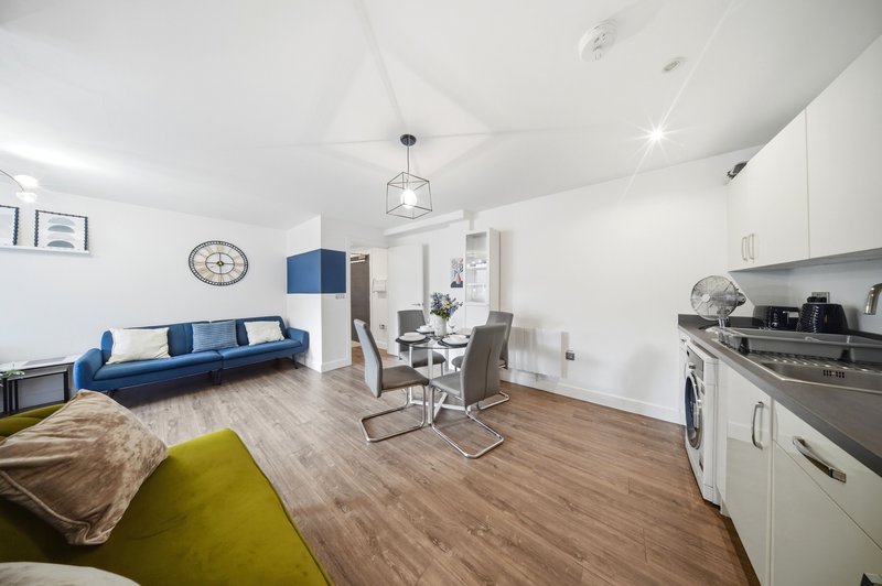 Open-plan studio with blue sofa, dining table, kitchenette and modern furnishings