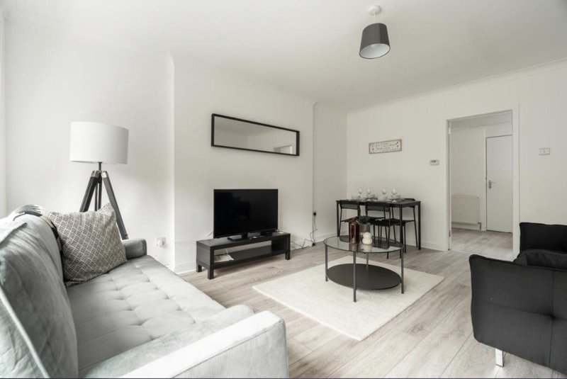 Modern living room with grey sofa, TV stand, bookshelf, coffee table and tripod floor lamp