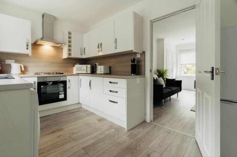 Modern kitchen with white cabinetry, dark worktops, built-in oven and open-plan layout