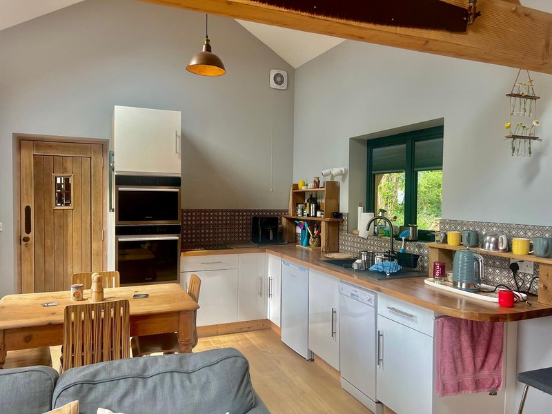 Modern kitchen with white cabinetry, wooden countertops, pendant lighting and dining area