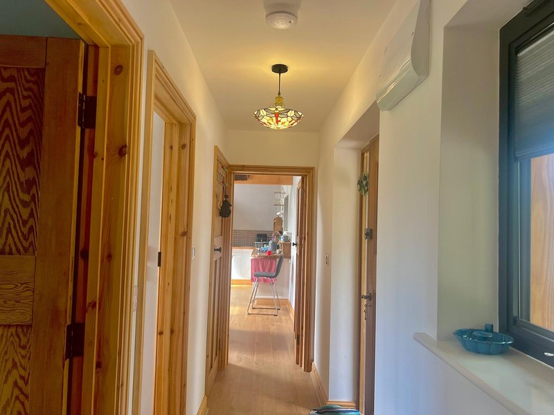 Hallway with wooden doors, pendant ceiling light, and cream-colored walls