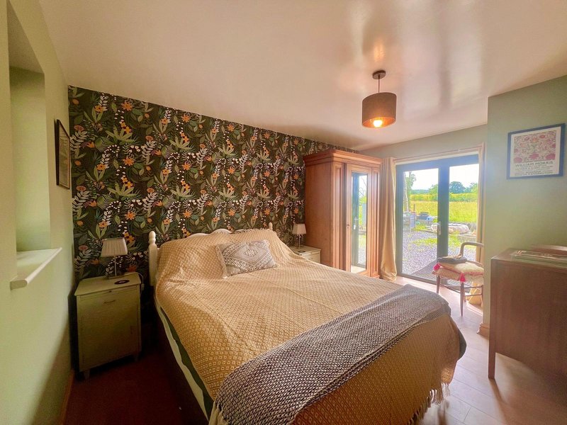 Bedroom with double bed, patterned headboard, pendant light, and glass doors to balcony
