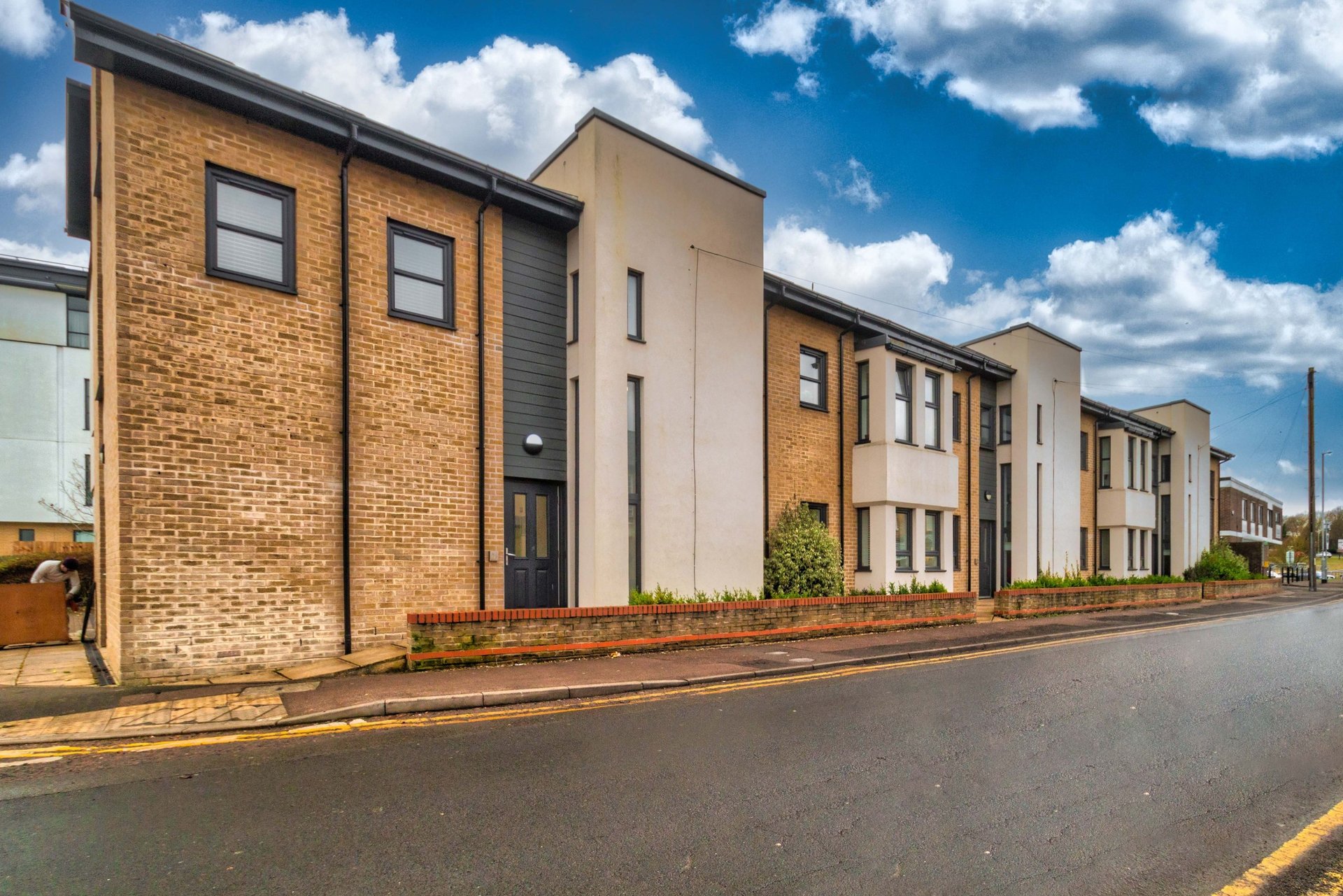 Modern brick and render residential buildings with street frontage and clear blue sky