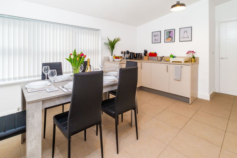Modern kitchen-diner with dining table, black chairs, wooden counters and vertical blinds