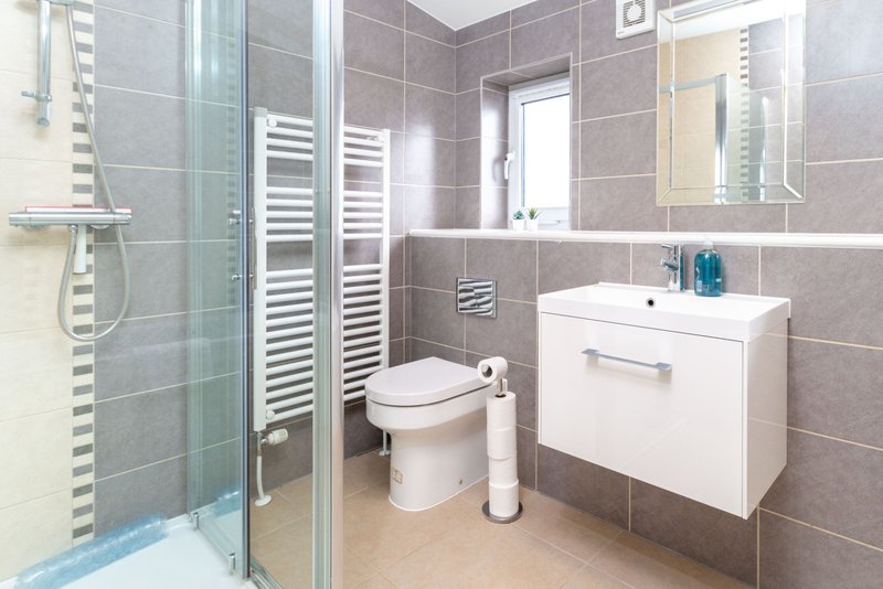 Modern bathroom with walk-in shower, white vanity unit, toilet and heated towel rail