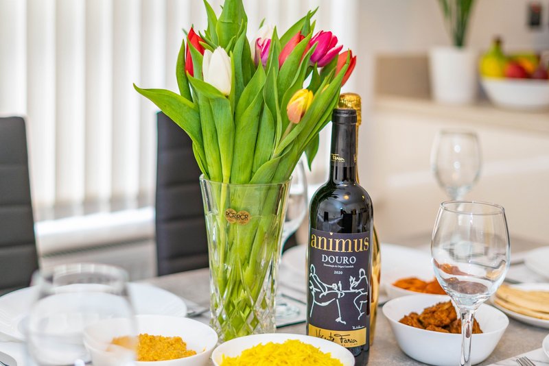 Dining table with tulips in vase, wine bottle, glasses and place settings