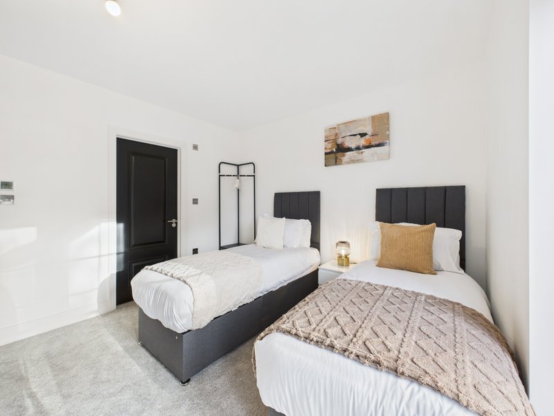 Bright twin bedroom with two single beds, black headboards, white bedding, and gold accents