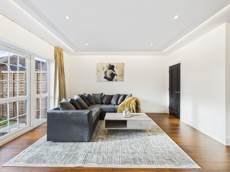 Modern living room with grey corner sofa, wooden floor, area rug and framed artwork