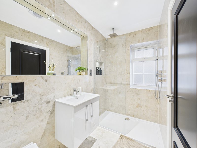 Modern bathroom with marble tiles, white vanity, mirror, and walk-in shower