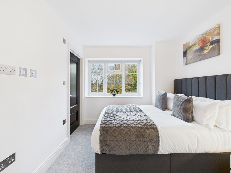 Modern bedroom with double bed, large window overlooking garden, and wall art