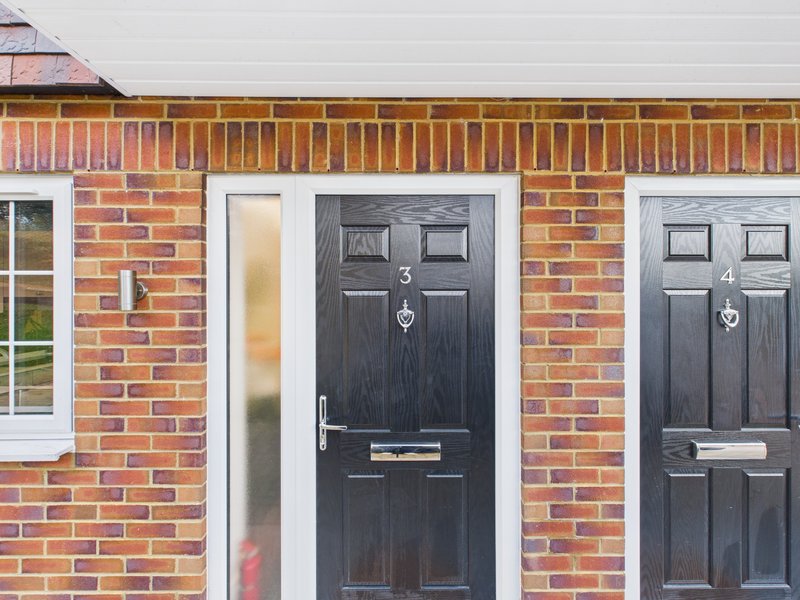 Brick terraced house exterior with two black front doors numbered 3 and 4