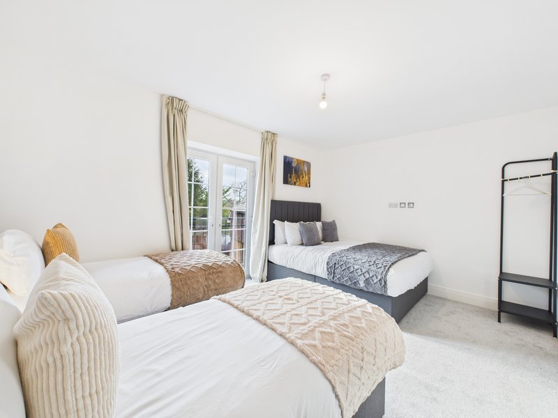 Bright twin bedroom with two single beds, cream bedding, patio doors and neutral décor