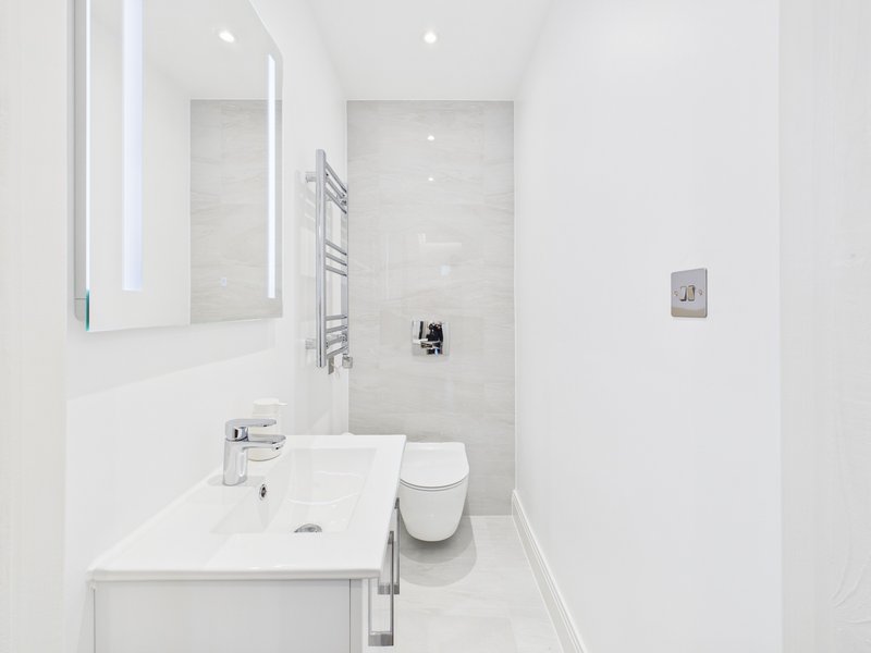 Modern white bathroom with sink, toilet, shower enclosure and heated towel rail