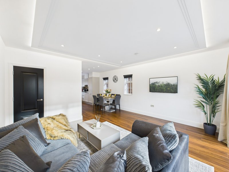 Modern living room with grey upholstered sofa, white coffee table, wooden flooring and potted plant
