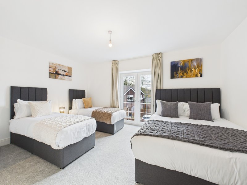 Spacious bedroom with two double beds, black headboards, white bedding and patio doors