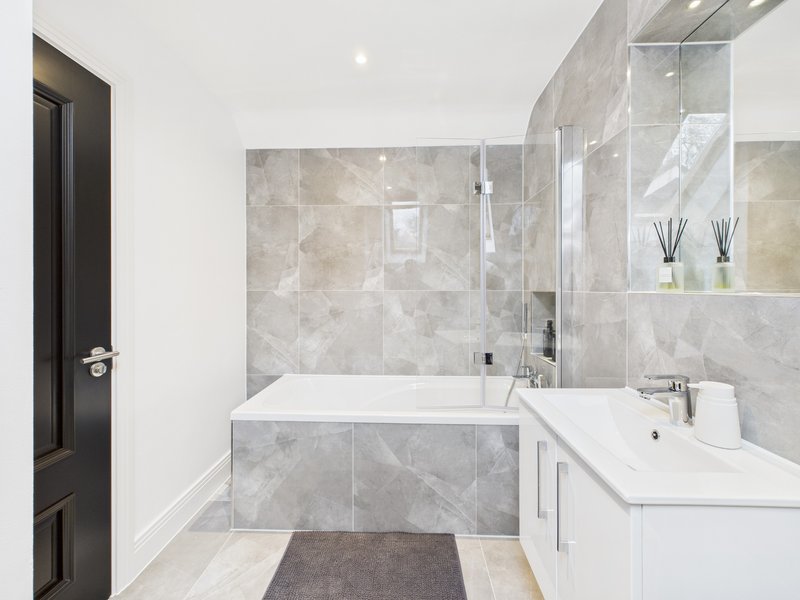 Modern bathroom with white vanity, grey marble tile, bathtub and shower enclosure