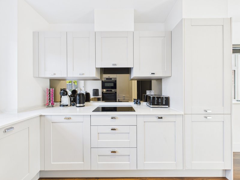 Modern white kitchen with appliances, counter space, and cabinet storage