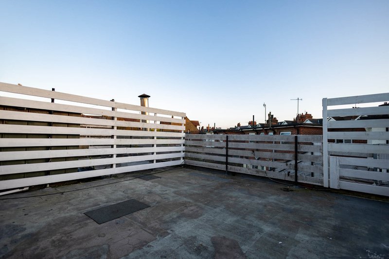 Rooftop terrace with metal fencing overlooking residential neighborhood at dusk