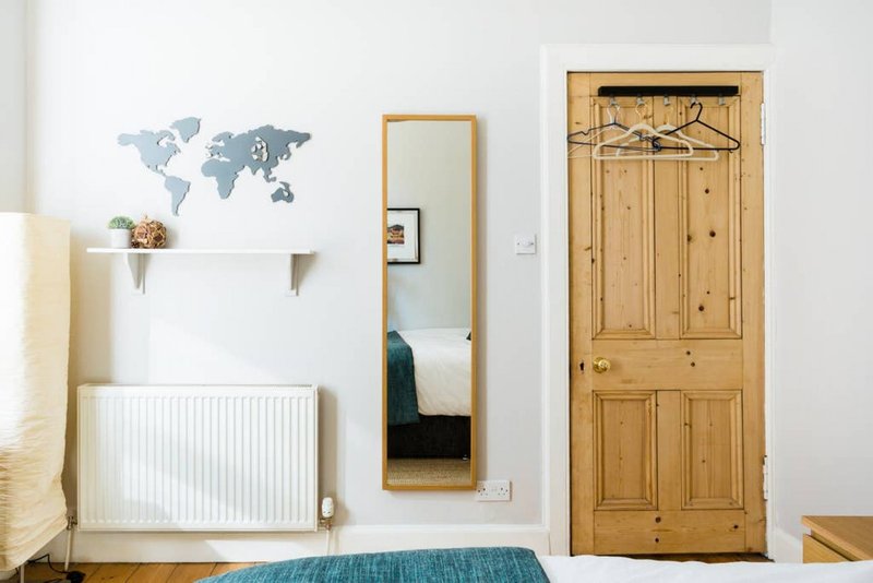 Bedroom with wooden door, radiator, wall shelf, and world map decal decoration
