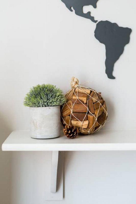White floating shelf with potted green plant, woven basket, and world map wall decor