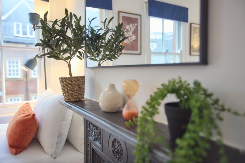 Windowsill with potted plants, decorative vases, cushions and framed artwork on wall