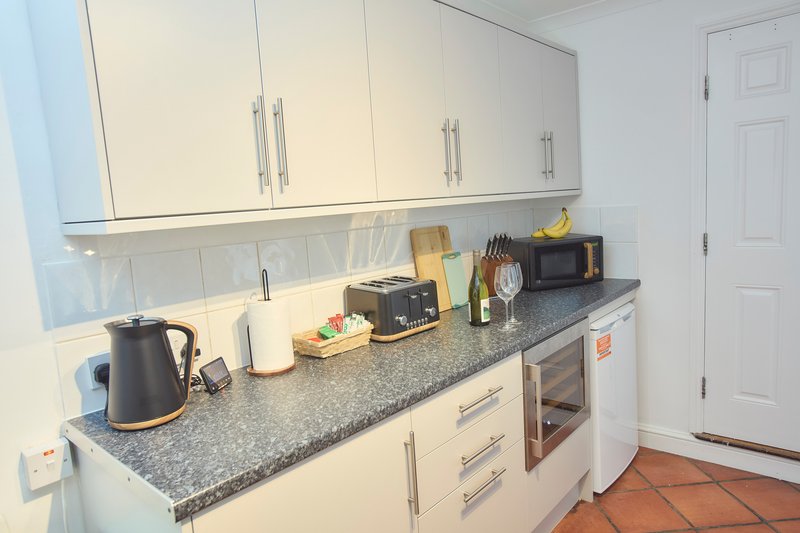 Modern kitchen with white cabinets, granite countertop, appliances and kitchenware