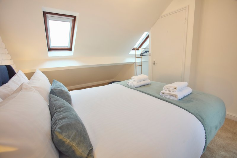 Attic bedroom with double bed, skylight windows, and folded towels on bench