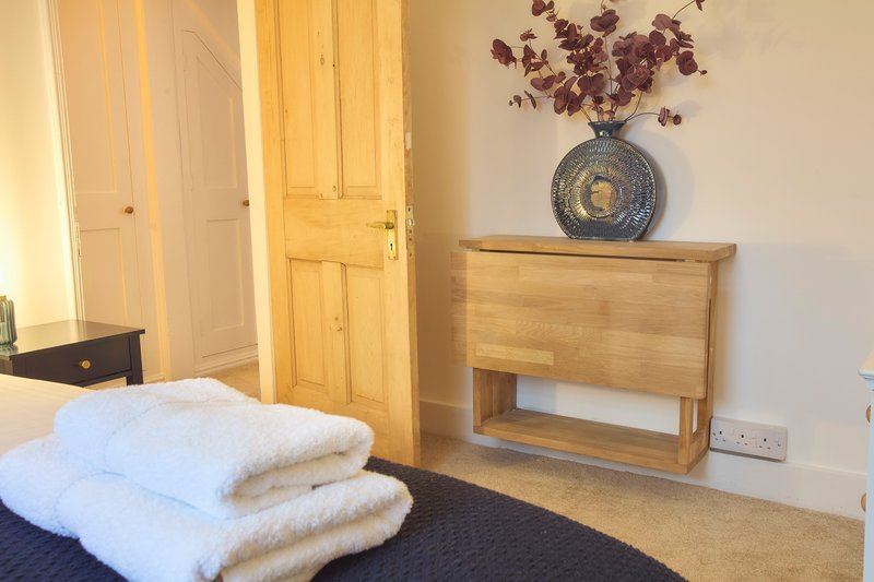 Bedroom with double bed, wooden wardrobe, bedside table with decorative vase and dried flowers