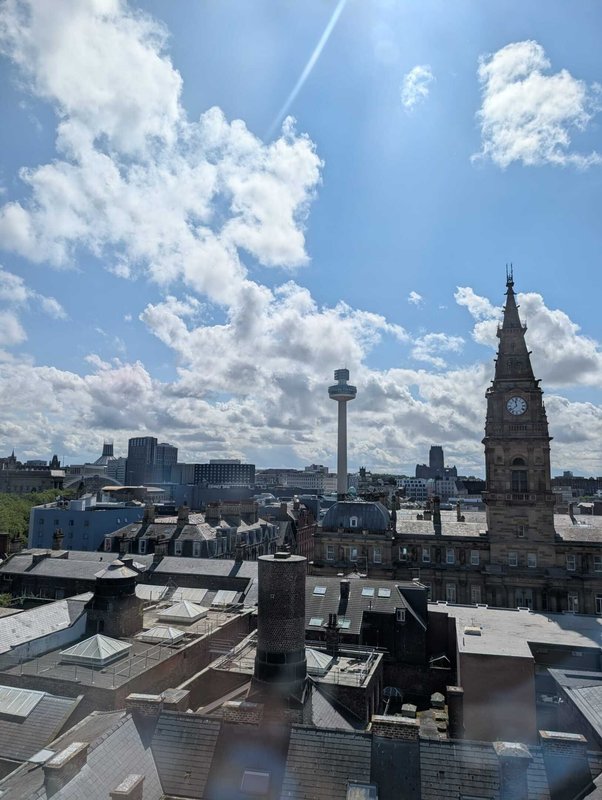 Urban rooftop view with clock tower and city skyline under blue cloudy sky