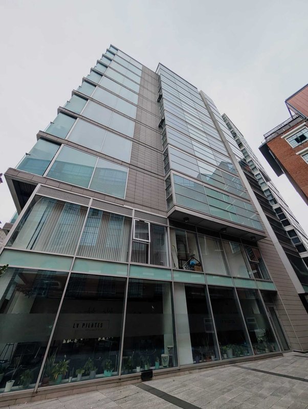 Modern multi-story residential building with glass and metal facade, ground-floor retail space