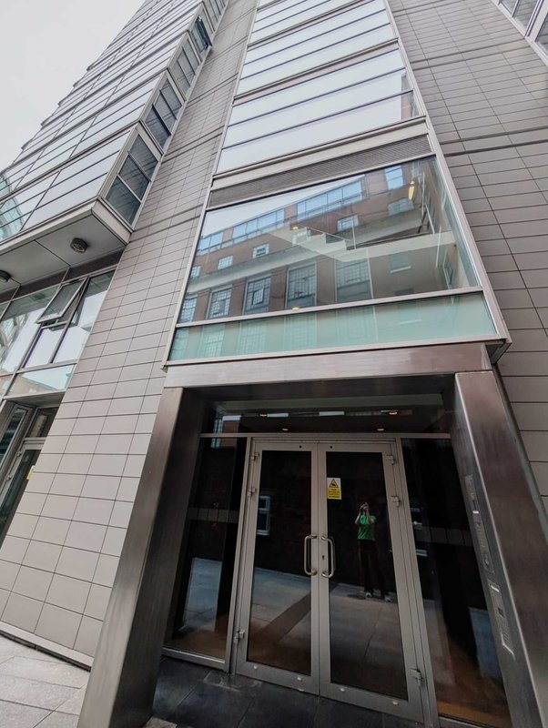 Modern residential building exterior with glass entrance doors and multi-story facade